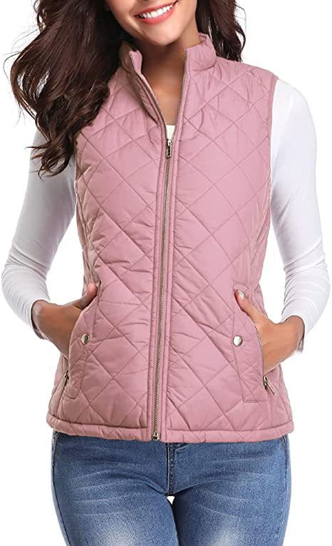 Chaleco acolchado de algodón color rosa suave para mujer con cuello alto, cremallera de longitud completa y dos bolsillos delanteros, que se lleva sobre una camisa blanca de manga larga.