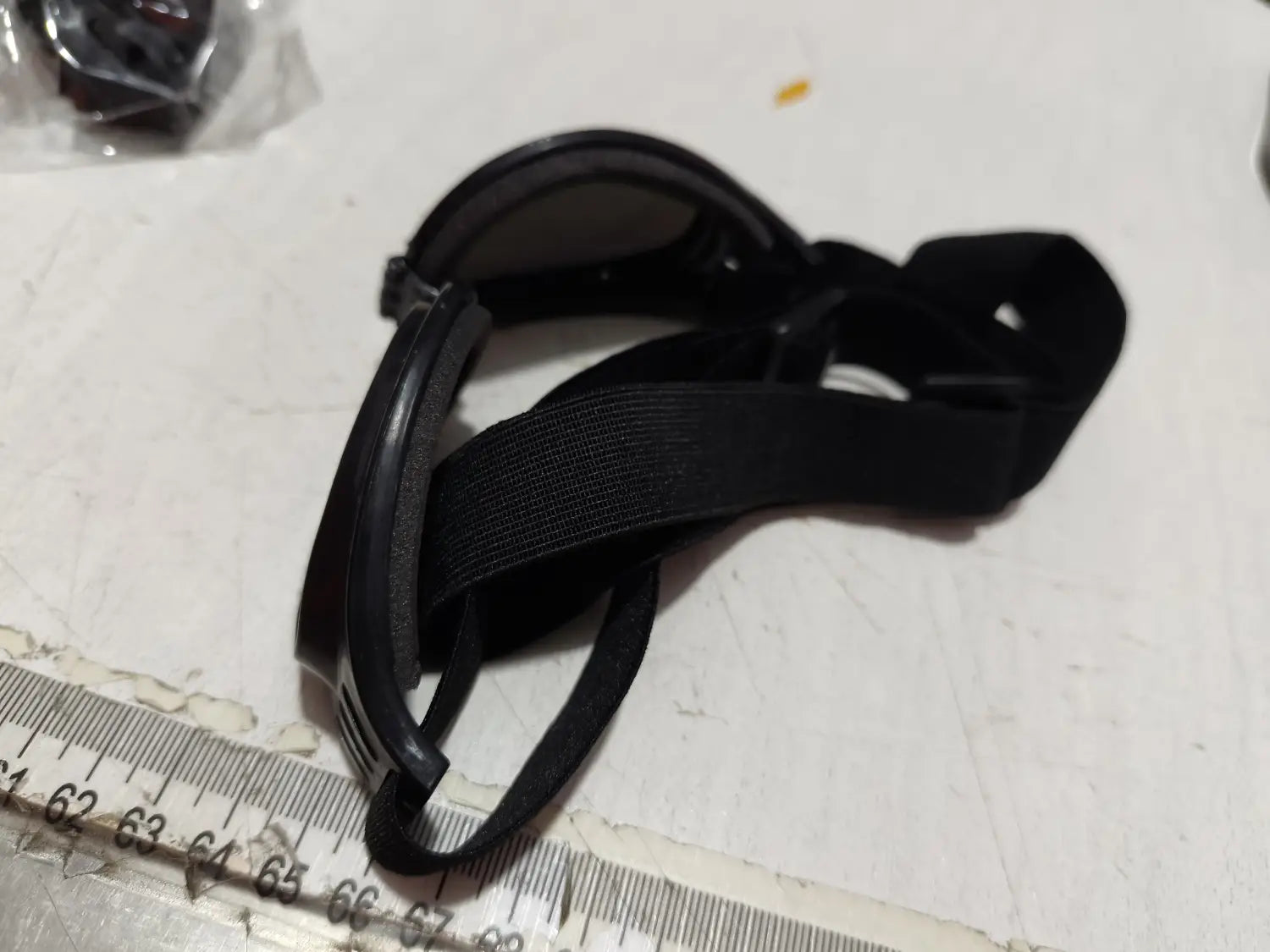 Gafas para perros con montura de plástico negra con protección UV y una correa elástica ajustable para mascotas de tamaño mediano.