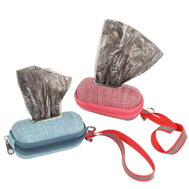 Two compact oval-shaped dog poop bag dispensers in blue and pink fabric with zipper closures and attached red reflective straps.