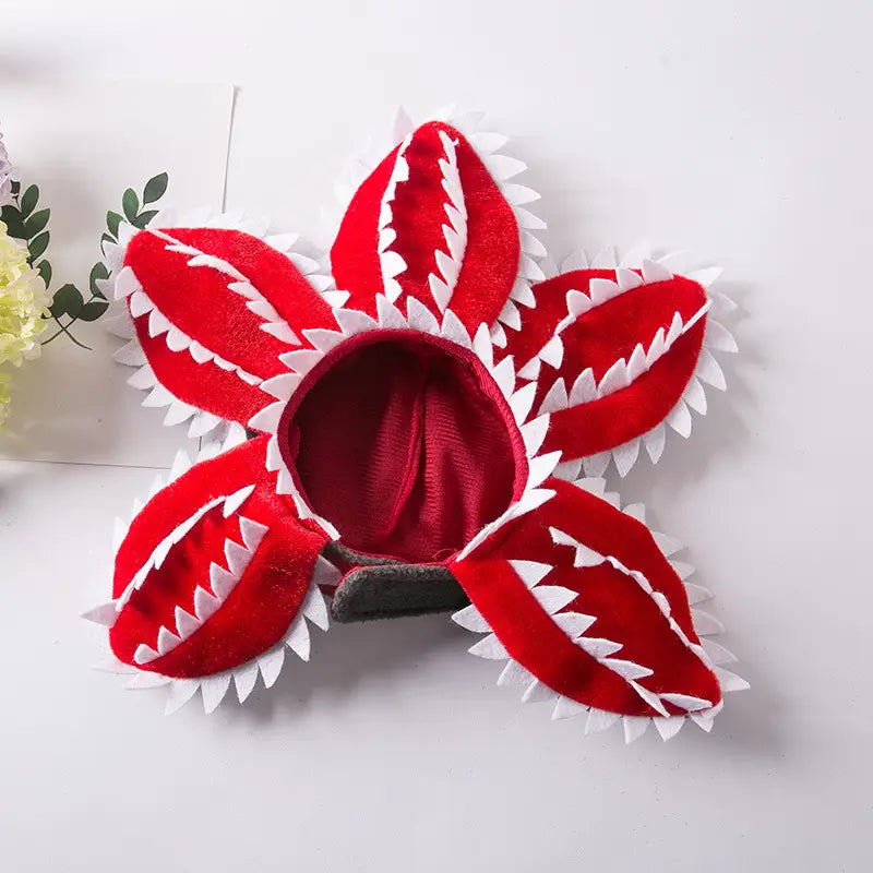 Red velvet flower-shaped pet costume with white jagged teeth trim designed as a plush carnivorous flower dog hat.