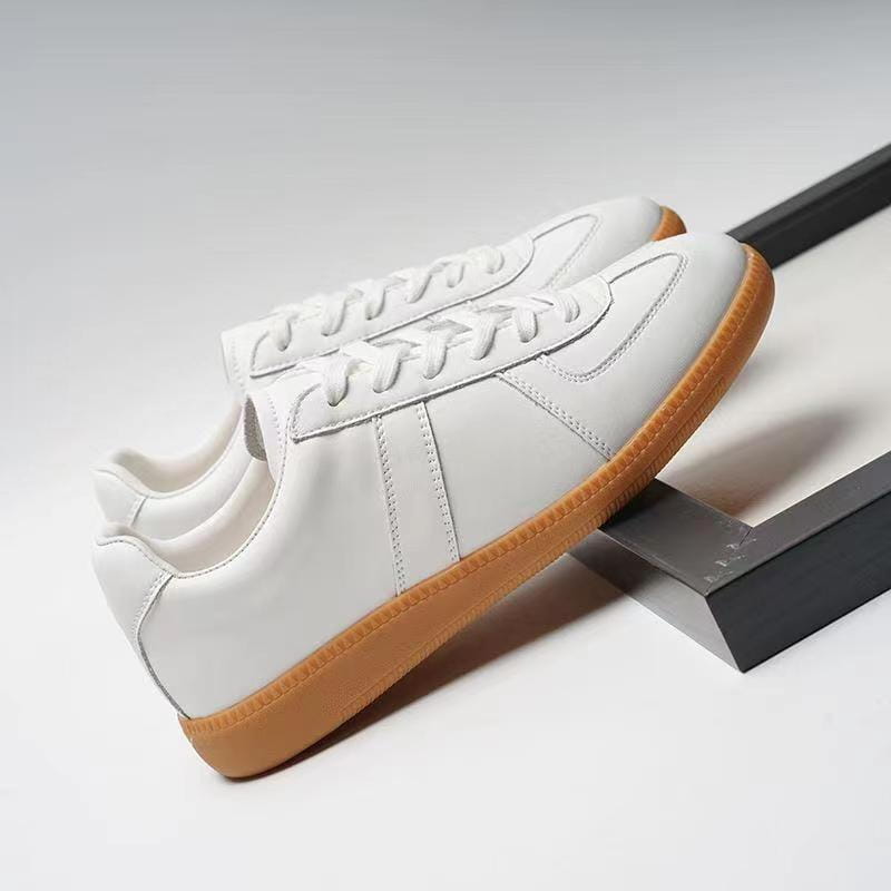 Weiße Ledersneaker mit brauner Gummisohle und klassischen Details in der Nahtausführung, ausgelegt als vielseitige Freizeitschuhe im Low-Top-Design.