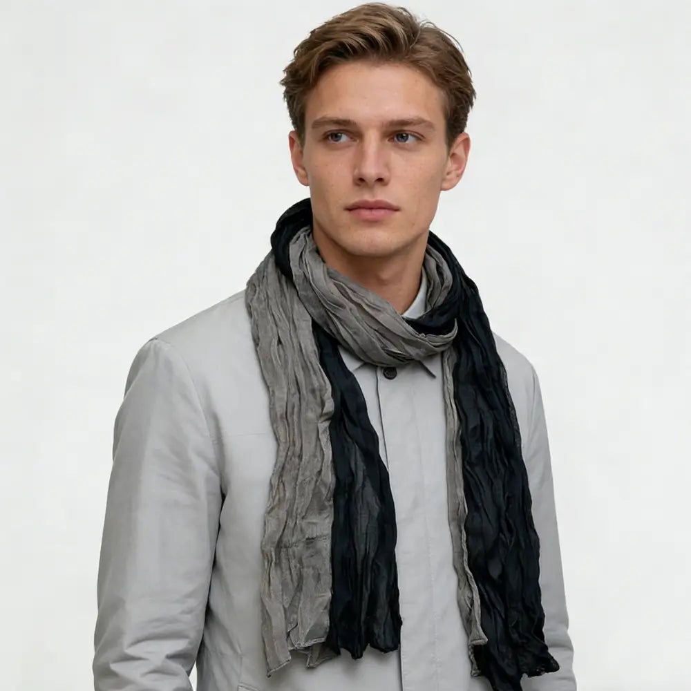 Una bufanda de color gris negro con textura y aspecto arrugado, con un diseño de dos tonos, drapeada alrededor del cuello.