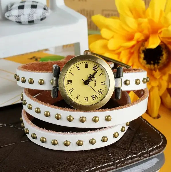 White leather wrap watch bracelet with gold-tone studs and vintage-style brass face featuring roman numerals.