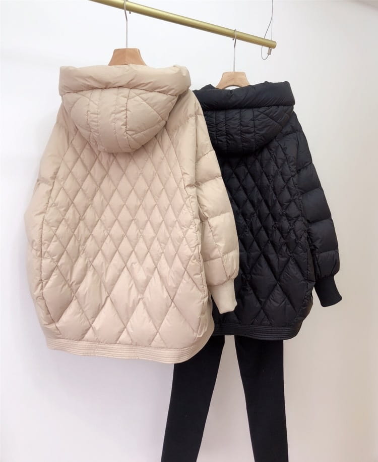 Beige and black quilted white duck down puffer jackets with loose hooded design hanging on wooden hangers for winter use.