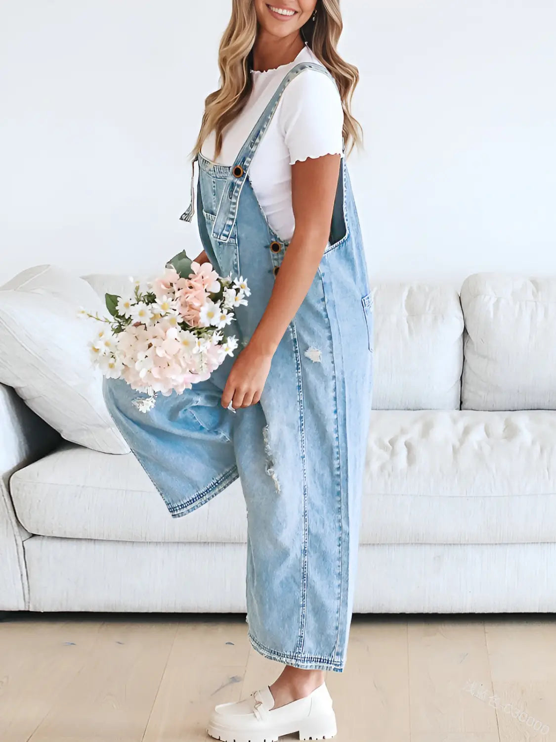 Women’s distressed denim overalls in light-wash denim featuring a relaxed wide-leg cut with subtle distressing and adjustable straps.