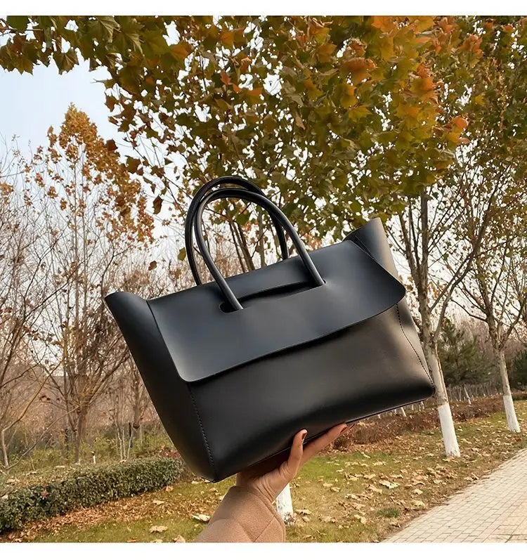 Black leather vintage structured tote bag with top handles and a sleek design.