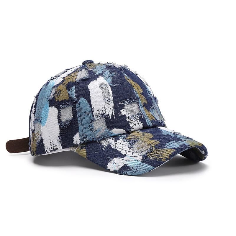 Une casquette de baseball en coton à projections de peinture vieillies, présentant un motif abstrait audacieux en marine, blanc, turquoise et de légers accents jaunes.