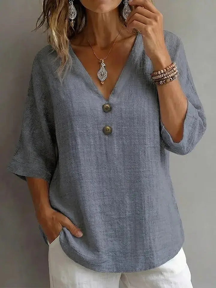 Light blue linen v-neck button top with three-quarter sleeves and two dark green buttons down the front.