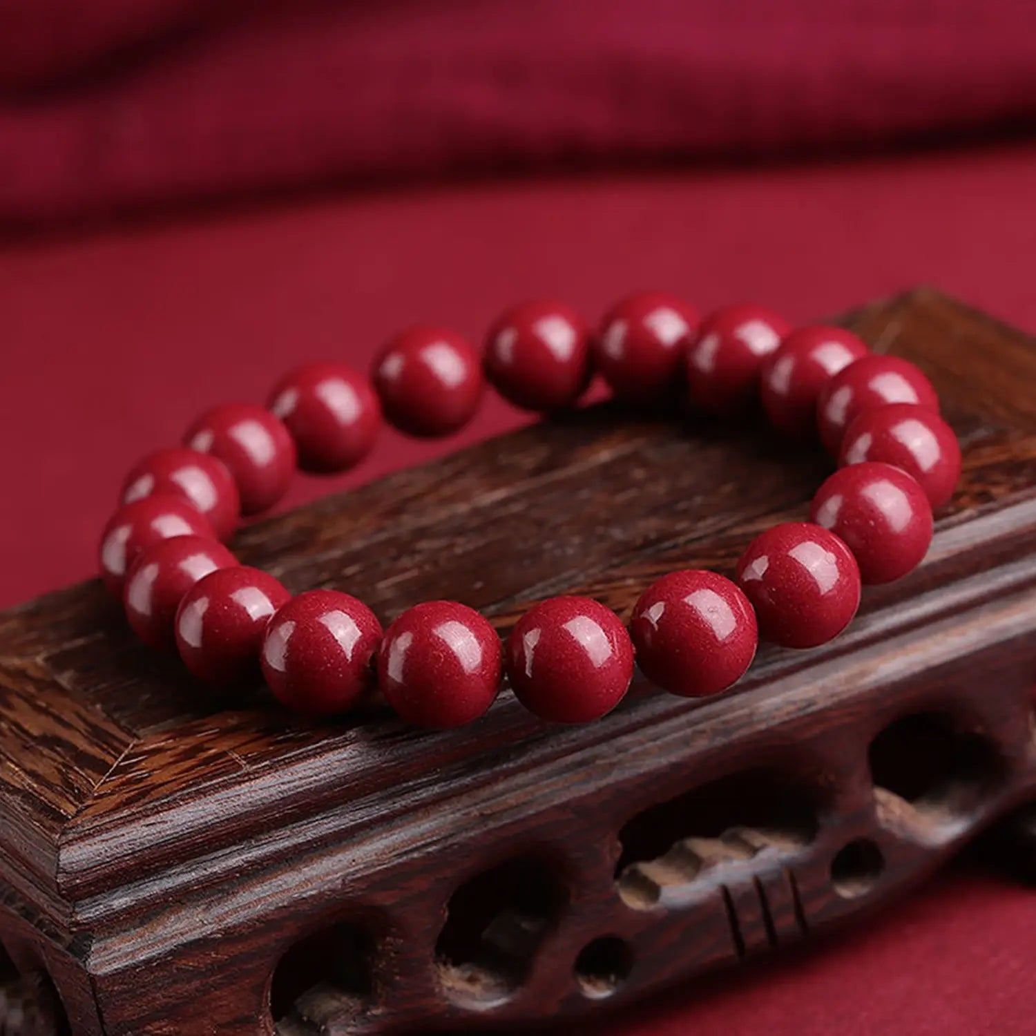 A polished red cinnabar bead bracelet featuring smooth, glossy, uniformly sized spherical beads arranged in a circular pattern.