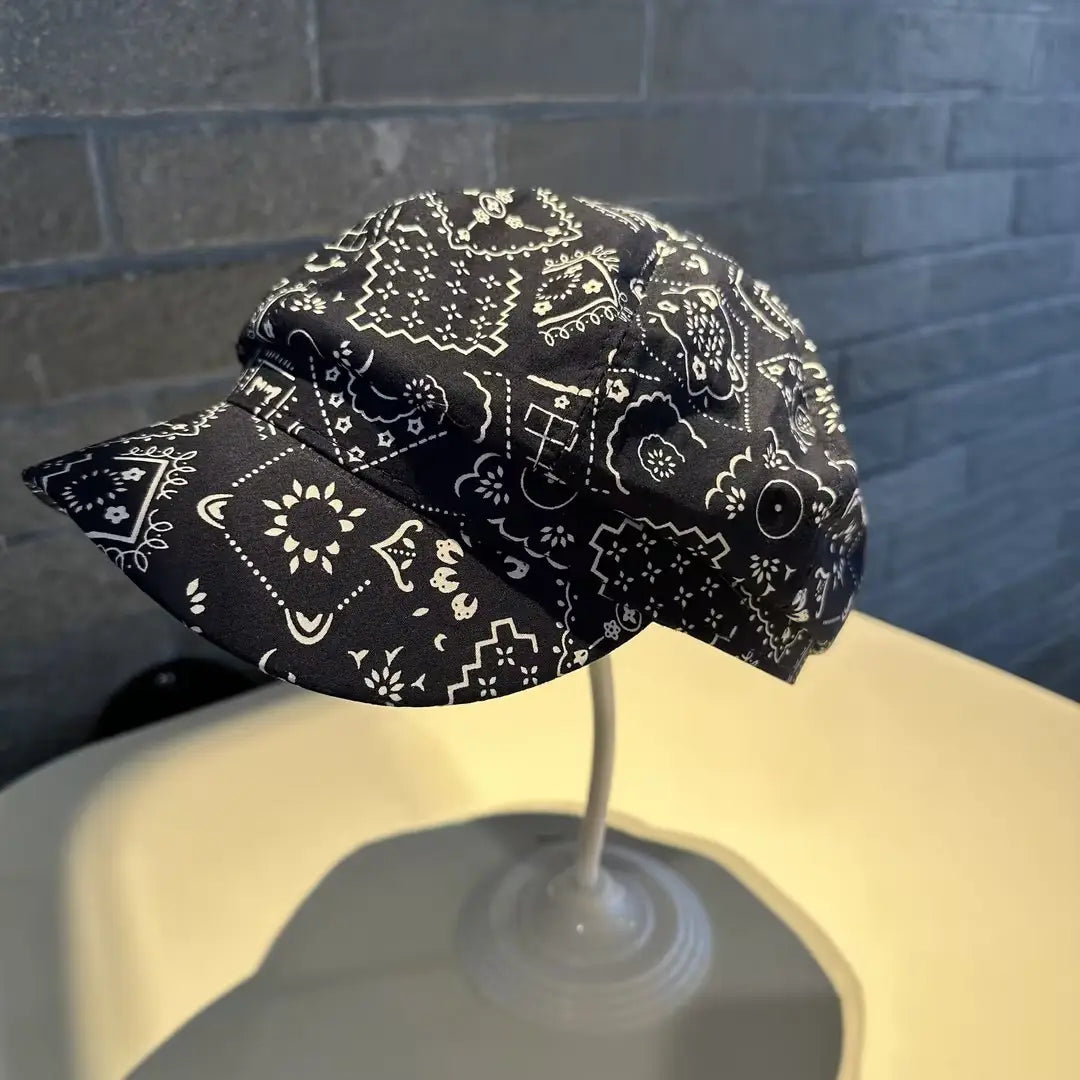 Floral newsboy cap for women made of black fabric with white bandana pattern featuring floral and geometric designs.
