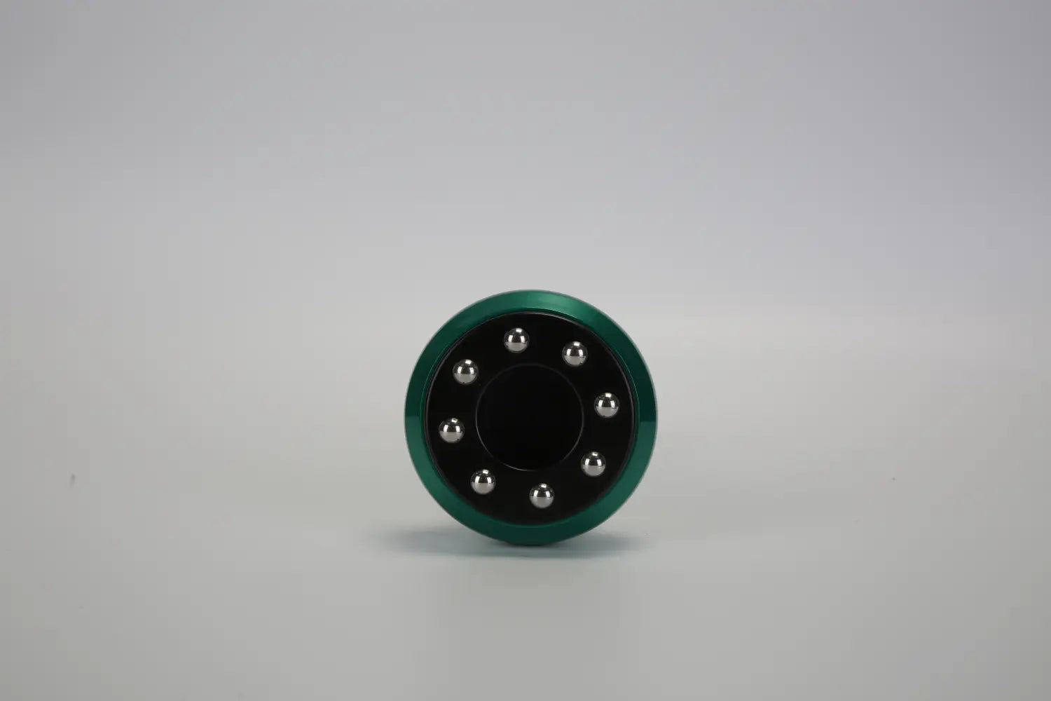 Husillo fidget spinner metálico verde con centro negro y ocho bolas plateadas dispuestas en un patrón circular, que forma parte del producto de copa eléctrica inteligente de 12 niveles y masajeador para celulitis.