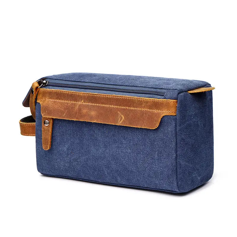 Blue canvas toiletry bag with tan leather accents and zipper closure for large portable travel storage case