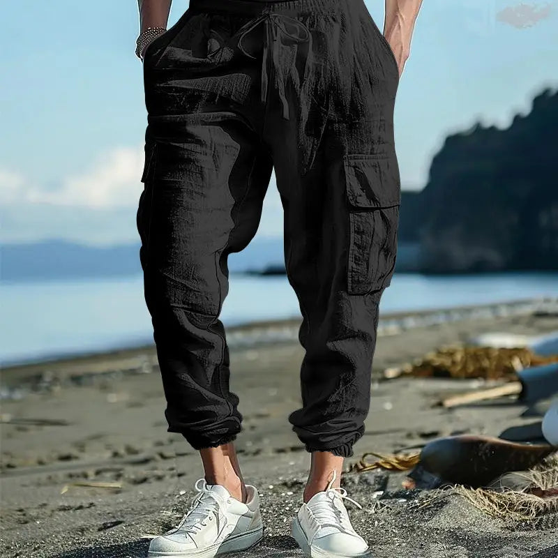 Black linen cargo pants featuring multiple pockets and a drawstring cuffed ankle waistband for men.