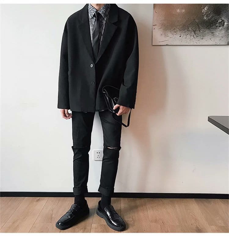 black leather crossbody bag with minimalist design and subtle stitching details complementing mens loose casual thin suit jacket.