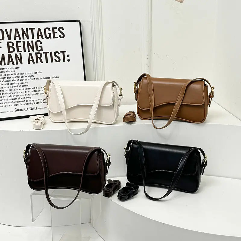 A sleek minimalist leather messenger bag in white brown burgundy or black with a smooth finish and an adjustable crossbody strap.