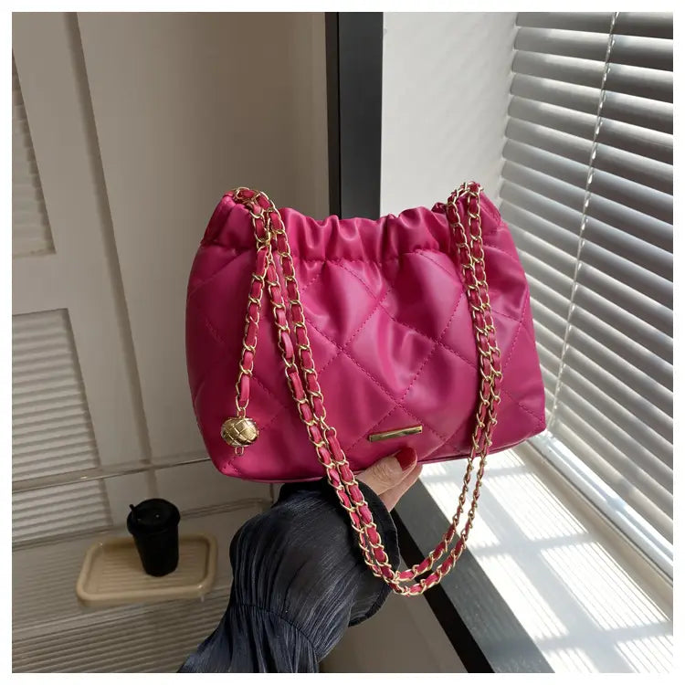 Vibrant fuchsia quilted faux leather crossbody bag with satin finish gold-tone chain straps and matching metallic clasp.