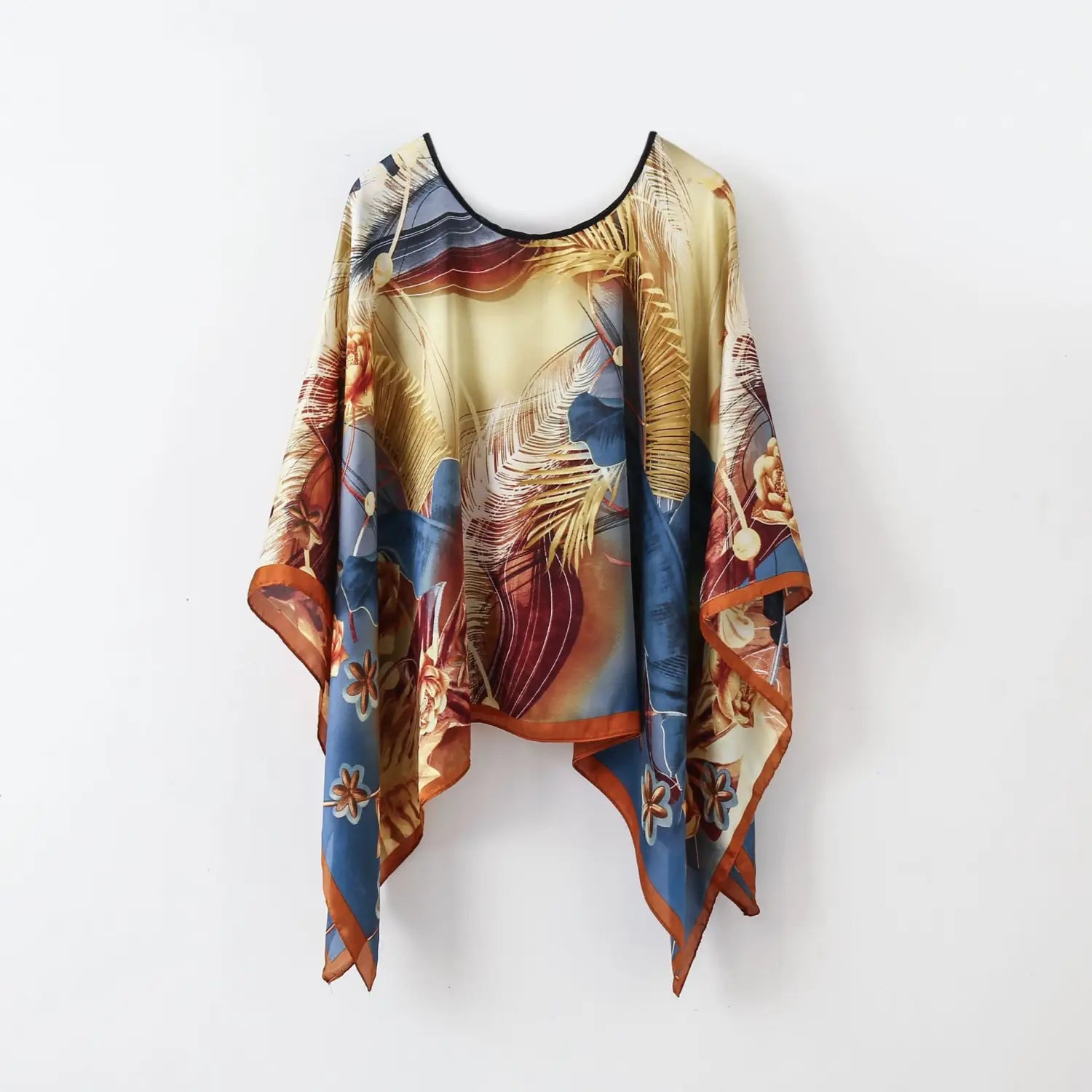 A printed silk patterned pullover shawl cape outerwear featuring a flowing wide-sleeved design in vibrant tropical print with golden feathers and blue floral motifs on a cream base with an orange-trimmed hem.
