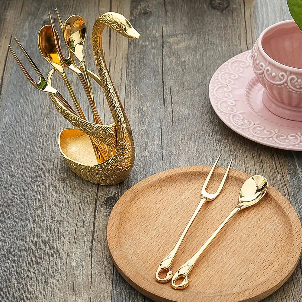Porte-ustensiles en forme de cygne doré, orné de détails délicats de plumes, contenant un assortiment assorti de cuillères et de fourchettes à dessert à l’aspect or, dans le Coffret de coutellerie Cygne en cuillères et fourchettes à dessert dorées.