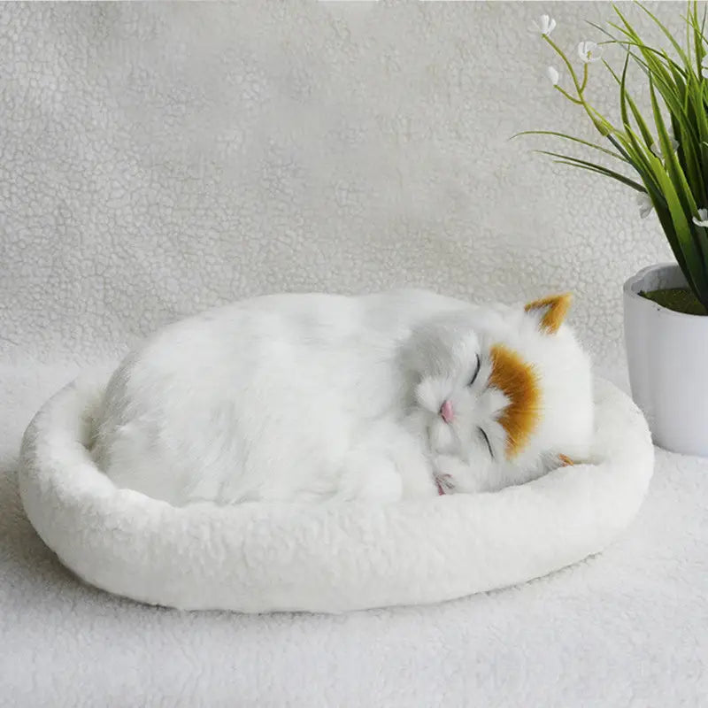A plush white and orange realistic breathing cat figurine made of soft material nestled in a round fluffy pet bed.