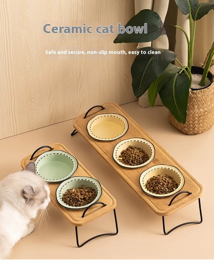 Set of elevated ceramic cat bowls with light green and yellow interiors in wooden trays with black metal legs for feeding pets.