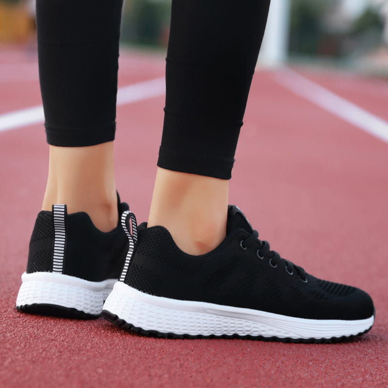 black mesh breathable athletic sneakers with white rubber soles and striped pull tabs shown from the back side