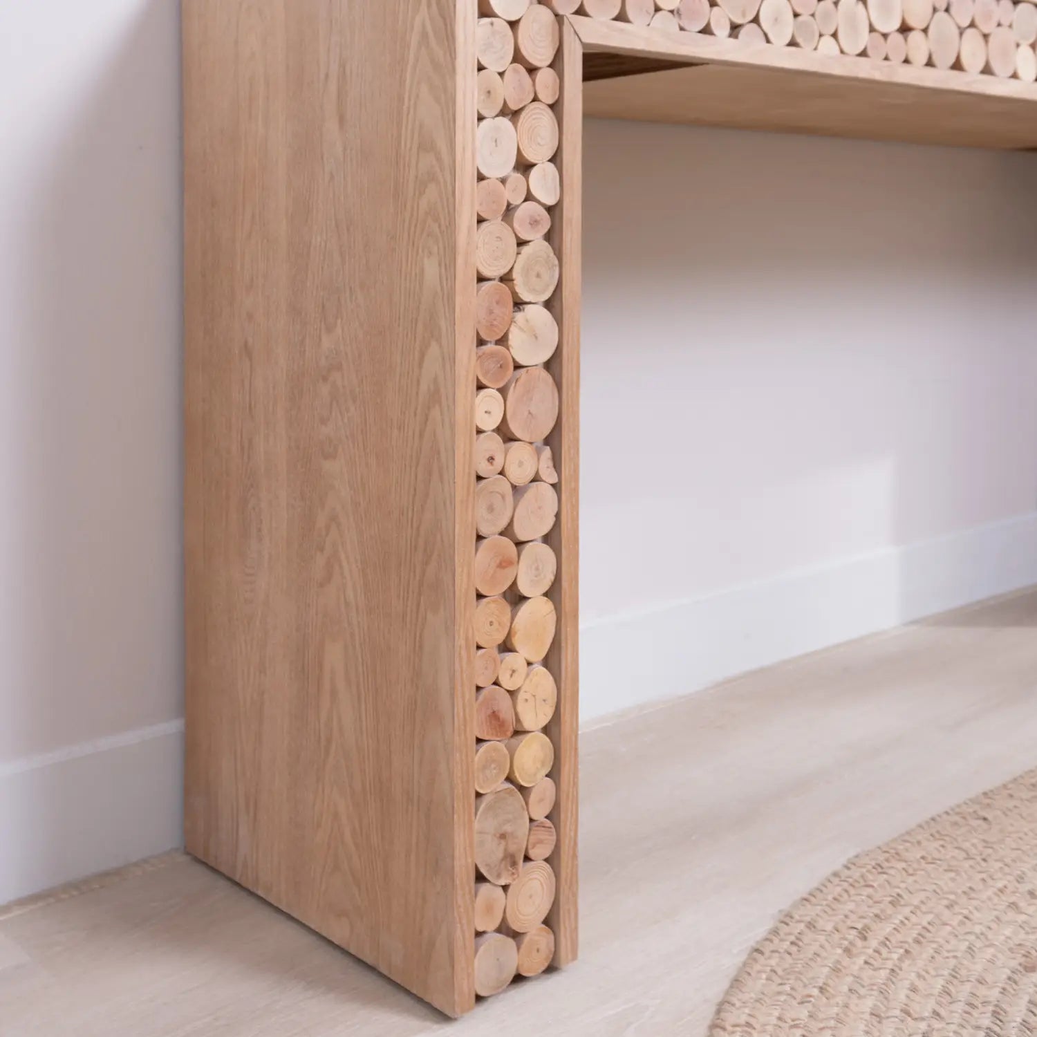Mesa consola rústica de madera con acentos de troncos naturales, con un diseño de madera moderno y un panel lateral distintivo hecho con cortes de madera circulares apilados en tonos marrón claro naturales.