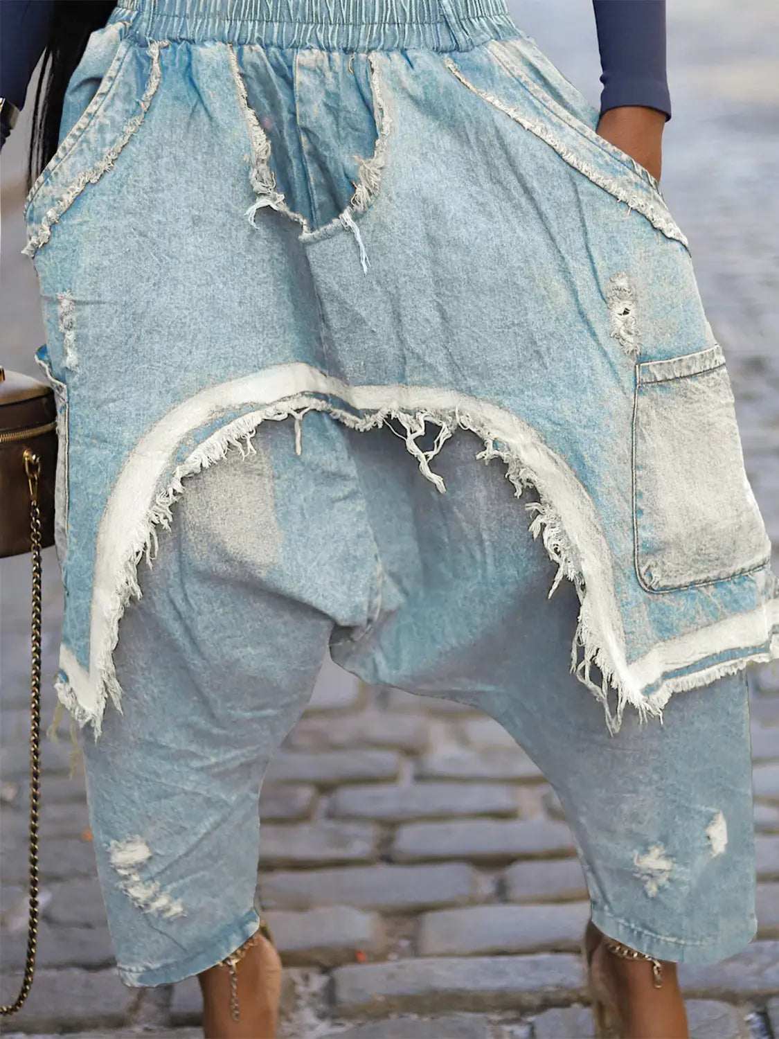 Hellblaue, abgenutzte Jeans-Haremshosen mit ausgefransten Kanten und Patchwork-Design, von der Rückseite präsentiert