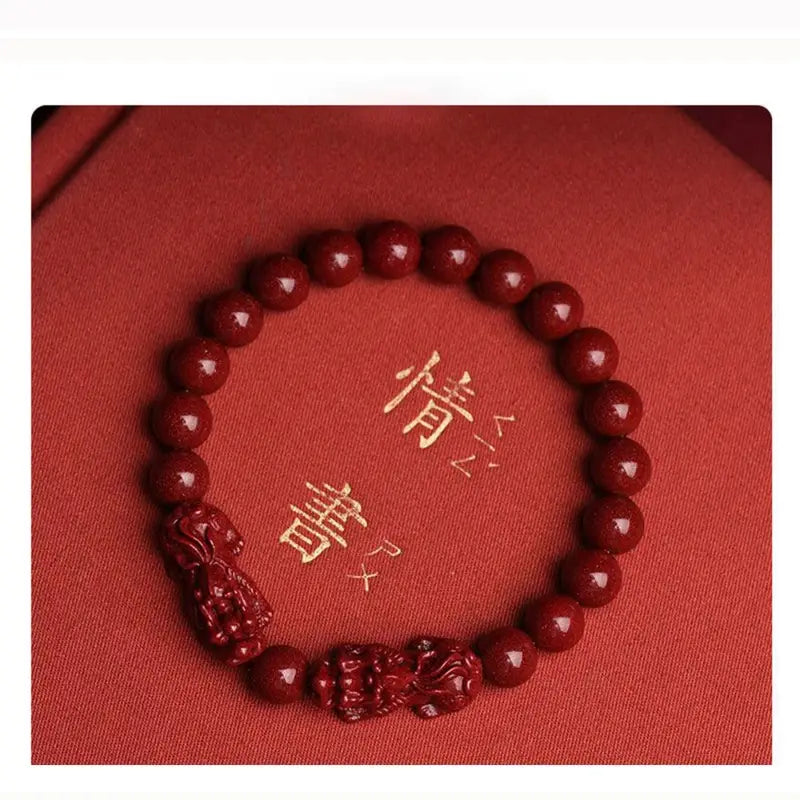 Hand carved purple gold cinnabar double Pixiu bracelet featuring polished red jade spherical beads and intricately carved dragon charms.