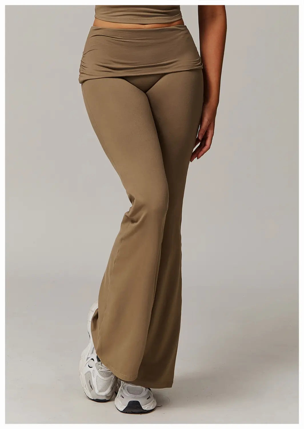 pantalones de yoga acampanados de cintura alta color arena hechos de tejido elástico con cinturilla fruncida.