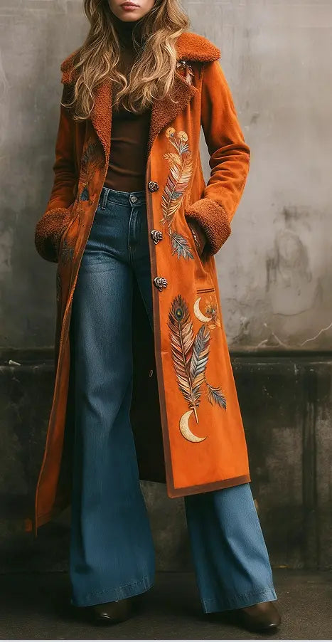 Ein langer Damen-Wollmantel aus orangefarbenem Cord mit plüschigem Shearlingbesatz und bestickten Motiven aus Feder- und Mondornamenten.