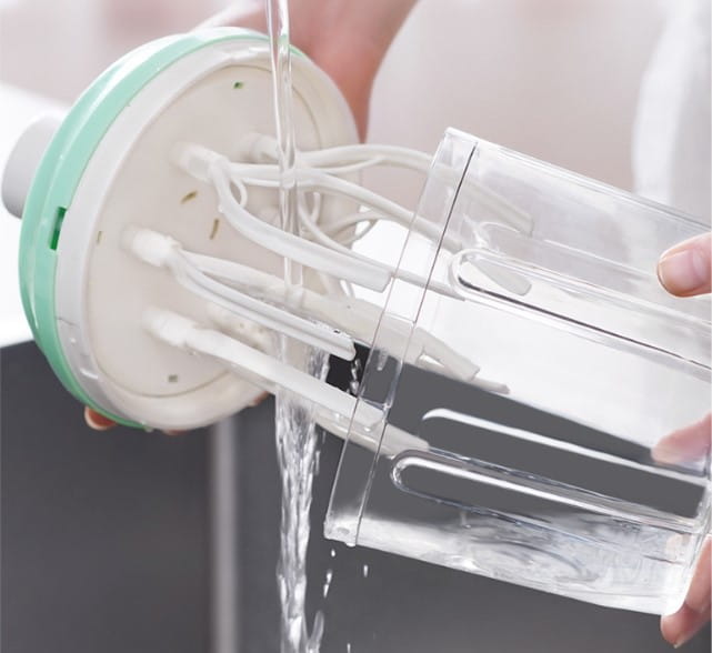 Ein klarer Kunststoff-Mixbecher mit integrierten Messern und einem weißen sowie minzgrünen Sockel für den manuellen Handkurbel-Eigquirl und den 1200-ml-Lebensmittelmixer.