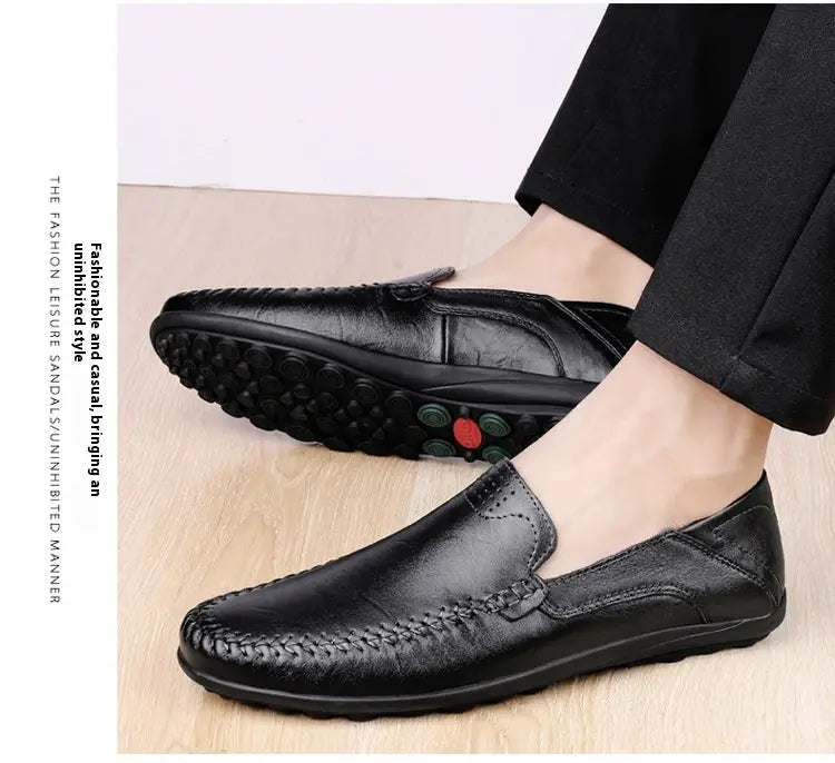 Schwarze Lederslipper für Herren mit genähter Verzierung und strukturierter Gummisohle, ausgelegt für den Business-Casual-Einsatz.