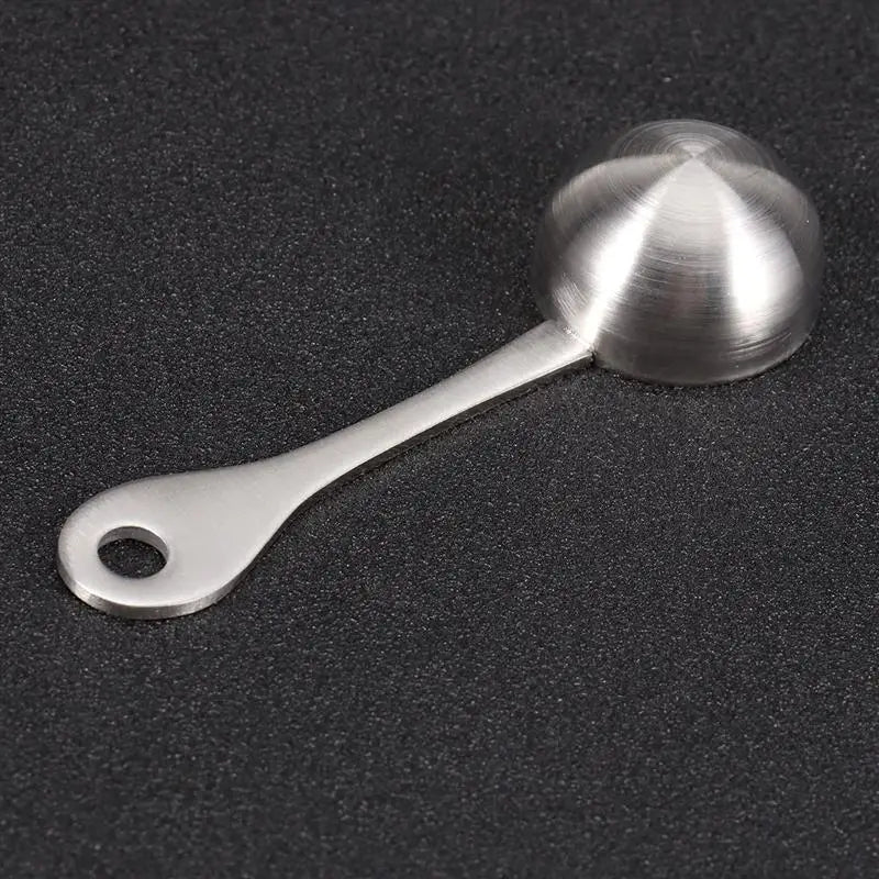 A sleek brushed stainless steel 304 measuring spoon with a rounded bowl and looped handle for kitchen use.