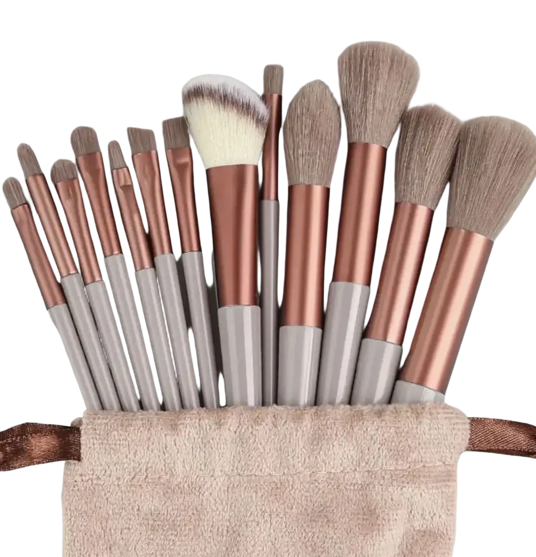 A set of 12 rose gold and gray makeup brushes with nylon brush material arranged in a blush-colored towel pouch