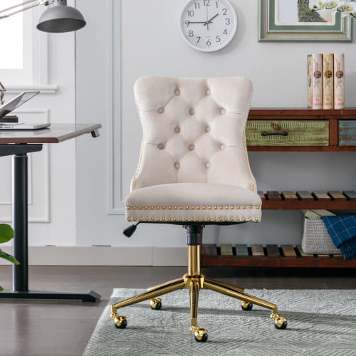 Silla de oficina de terciopelo color crema con botones tipo capitoné, base metálica de tono dorado y remate con tachuelas, diseñada para uso en oficina.