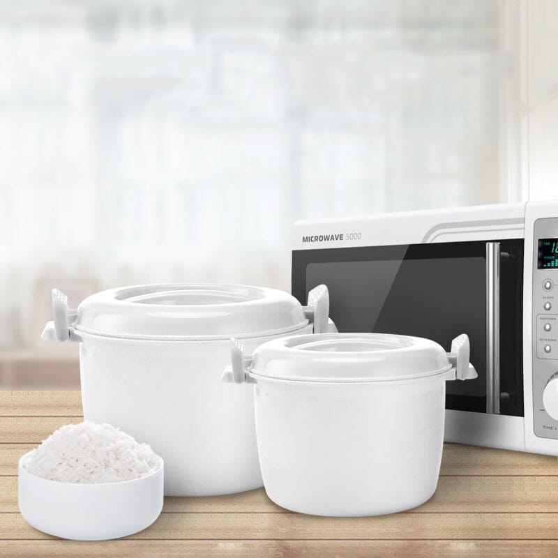 White microwave-safe rice cooker containers with steamer lids and side handles displayed with a small bowl of cooked white rice.