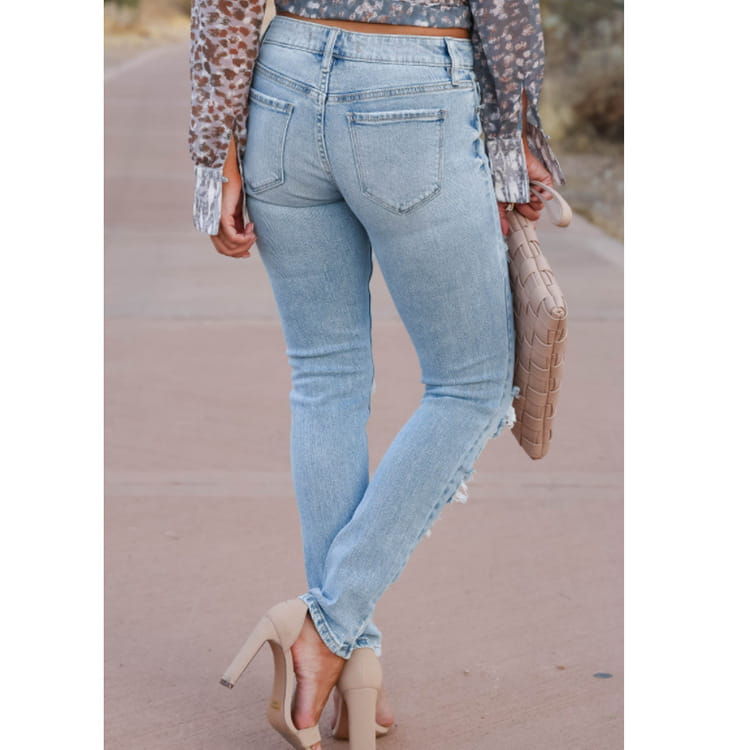 Pantalones vaqueros ajustados tipo skinny con efecto desgastado y roturas en mezclilla de lavado claro, con corte entallado y detalles deshilachados a lo largo de la pierna exterior.