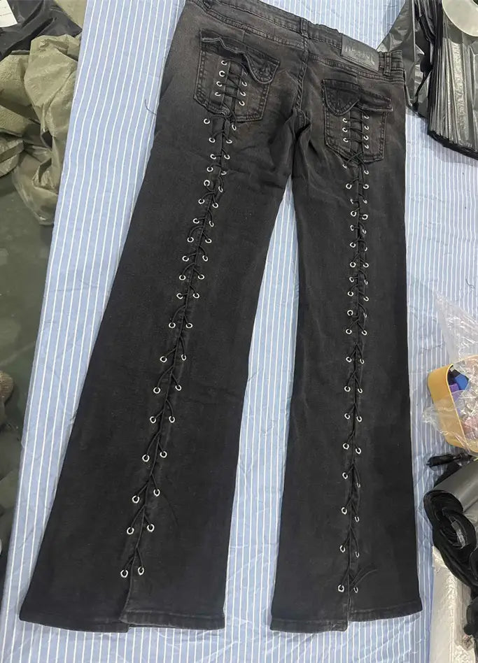 Jeans de mezclilla de tiro bajo tipo campana en negro con detalles de encaje con cordones a lo largo de las costuras exteriores, elaborados con material de mezclilla resistente.
