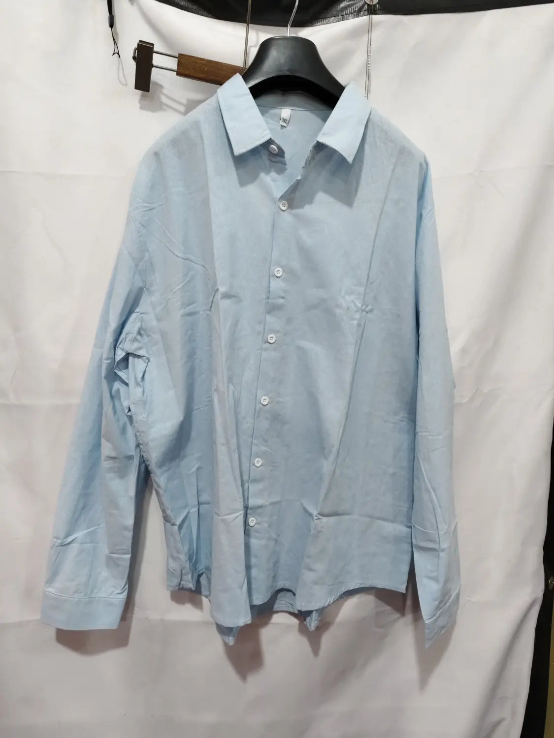 Light blue men linen casual button down shirt with long sleeves hanging on a black hanger.