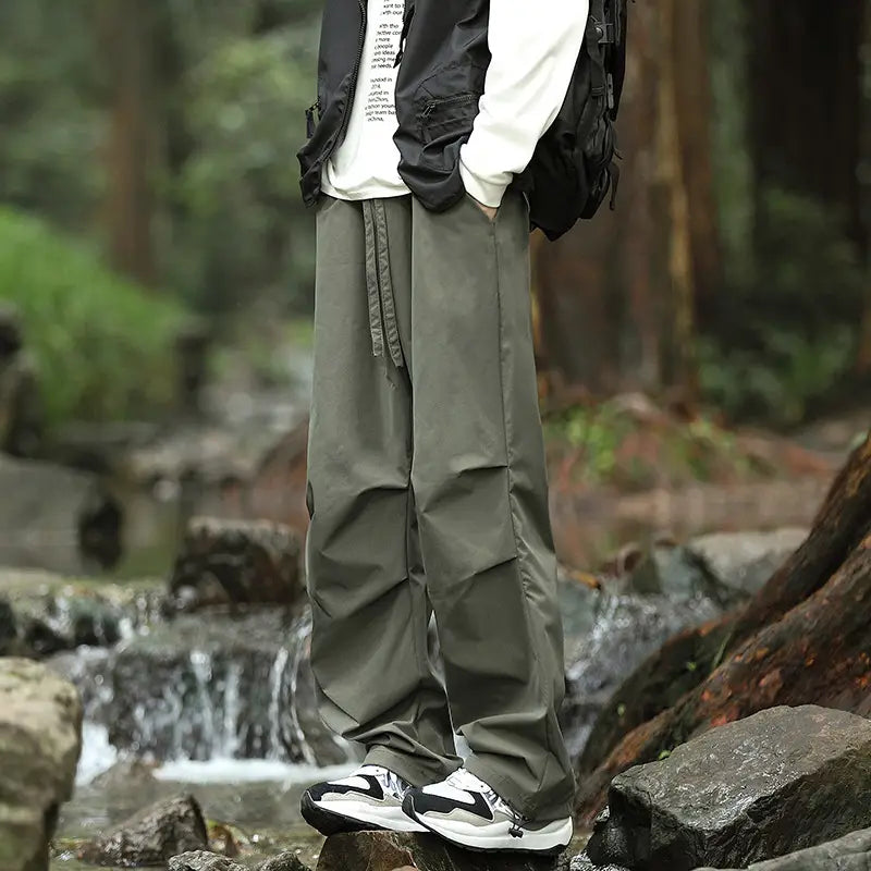 olive green pleated cargo hiking pants for men and women with a drawstring waistband and multiple pockets displayed from the front.