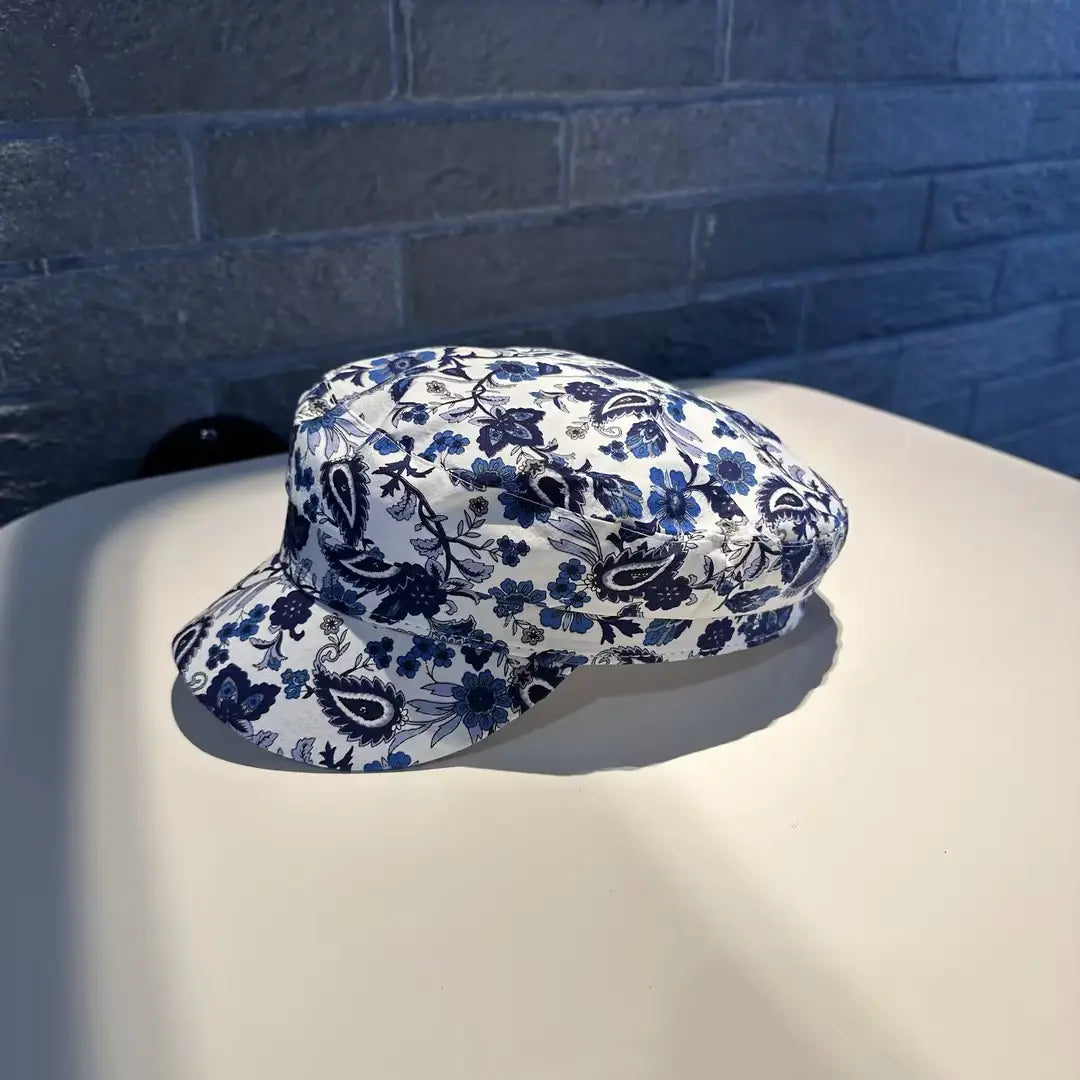 Gorra tipo bucket hat blanca con un patrón detallado de flores azules y paisley en tela impresa estilo coreano.