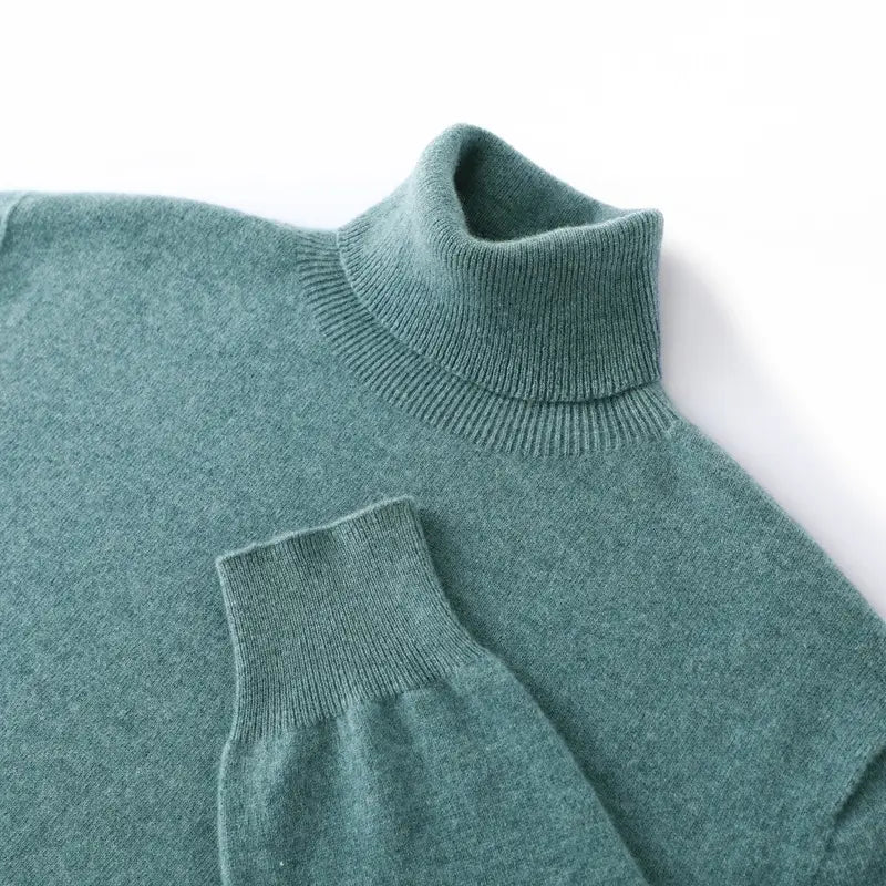 Pull col roulé en cachemire pour homme, forme ample, en vert canard mat et doux, avec une texture en maille fine et des poignets côtelés.
