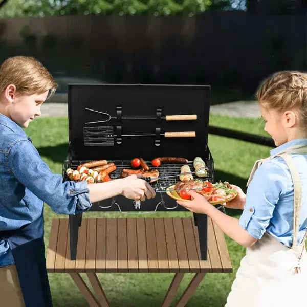 Black portable charcoal grill 44cm folding square bbq steel with wooden handles and metal grilling tools attached to the side.