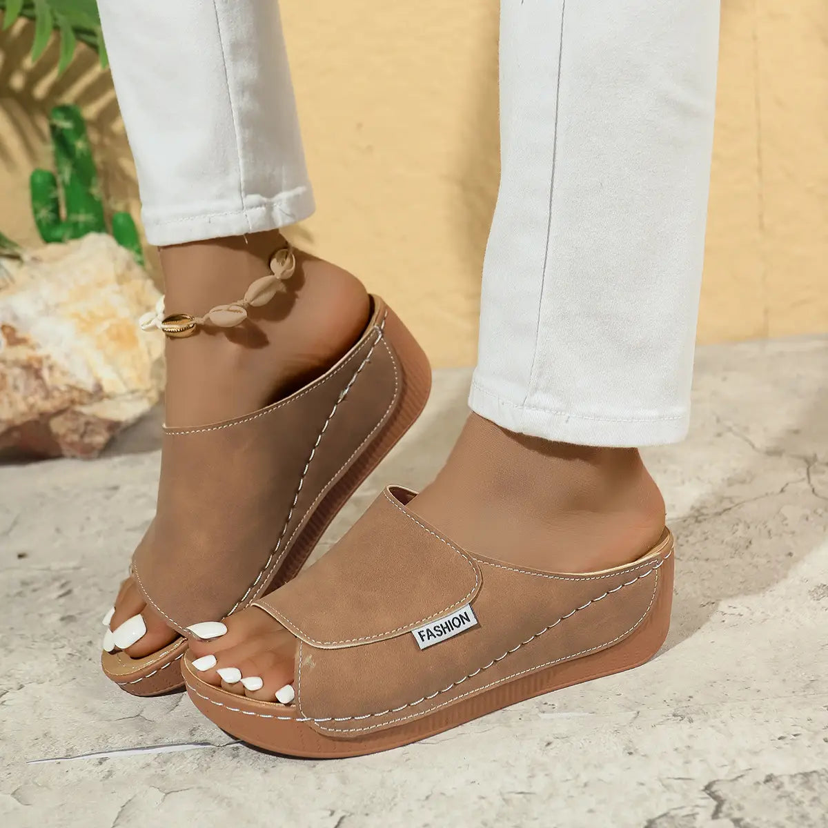 Sandales d’été à plateforme compensée à bride glissante pour femmes beige, avec un dessus souple de type cuir, des coutures blanches contrastantes et un design minimaliste comportant une petite étiquette de mode sur le côté.