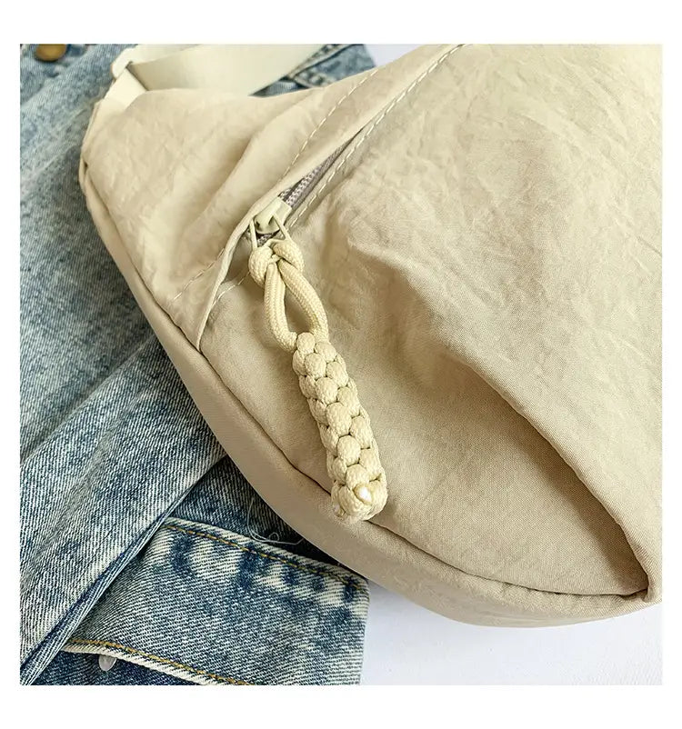 Beige nylon crossbody bag made of canvas with a braided rope zipper pull for large capacity hobo shoulder use.