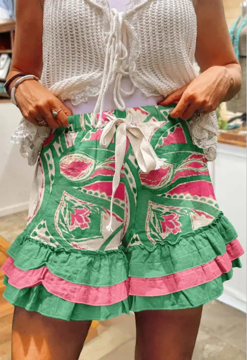 Grüne und pinke Shorts mit floralen Mustern, gerafften Shorts mit weißem Tunnelzugbund, gezeigt mit Karomosaik-A-Linien-Rock.