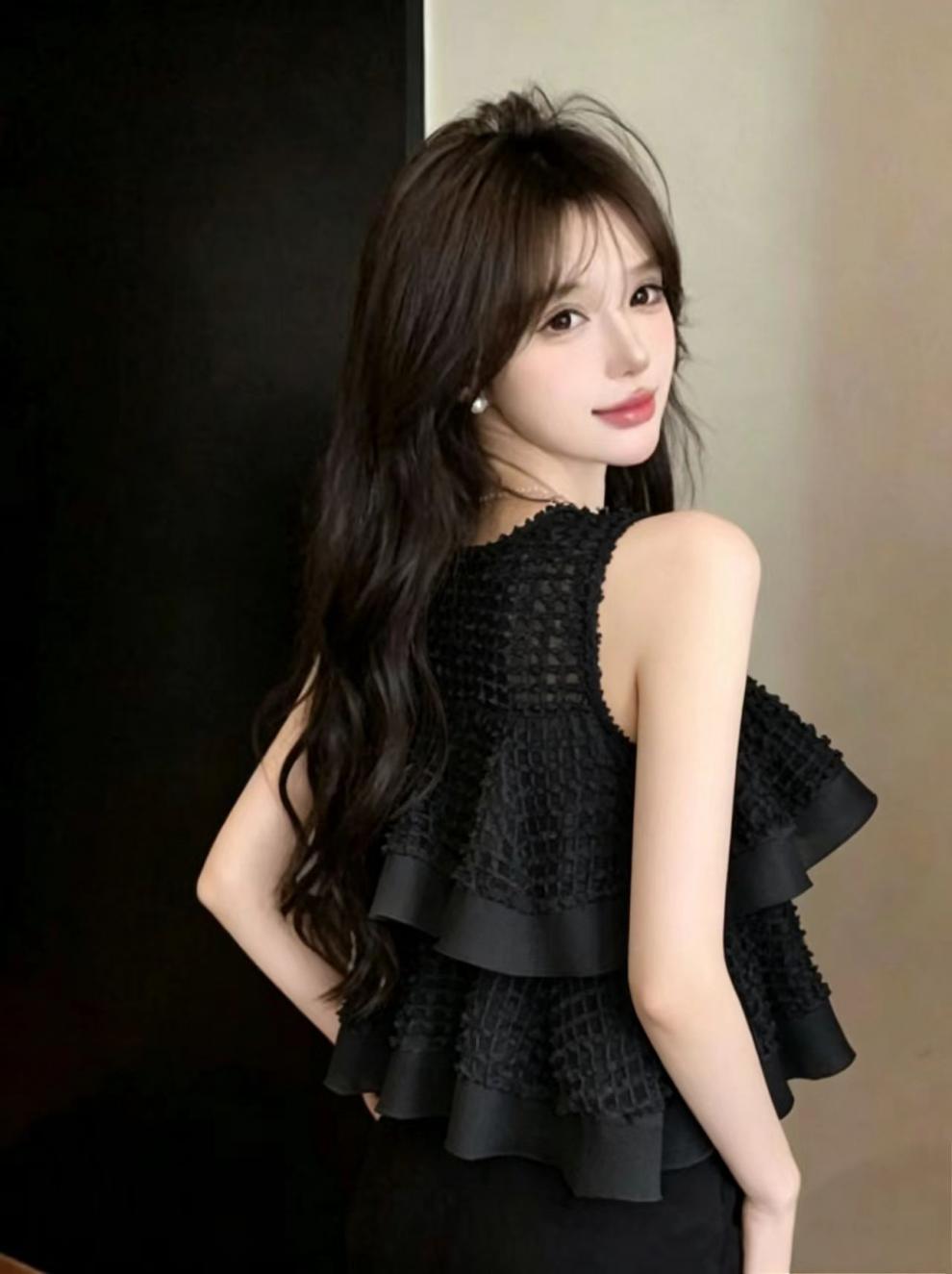 Black ruffled sleeveless blouse featuring layered frill details and textured fabric for an elegant look.