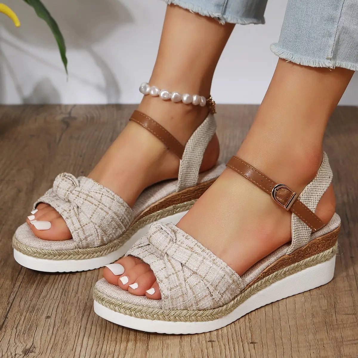 beige woven fabric wedge sandals with brown leather buckle straps and a braided rope sole designed for stylish summer wear