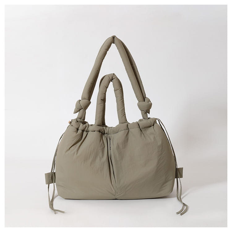 A soft olive green quilted puffer tote bag made of lightweight nylon with knotted handles and a drawstring closure.