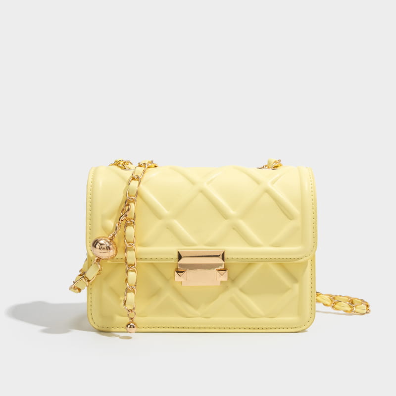 A pale yellow quilted crossbody bag made of soft material with a gold-tone chain strap and clasp.